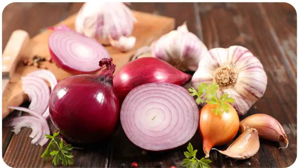 an assortment of onions and garlic on a wooden table