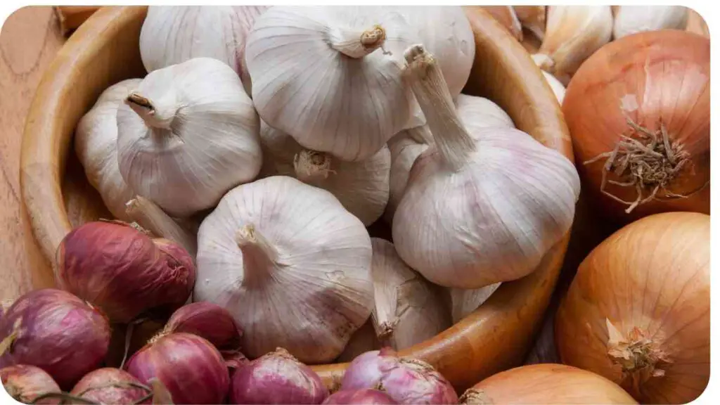 garlic and onions in a wooden bowl on a table